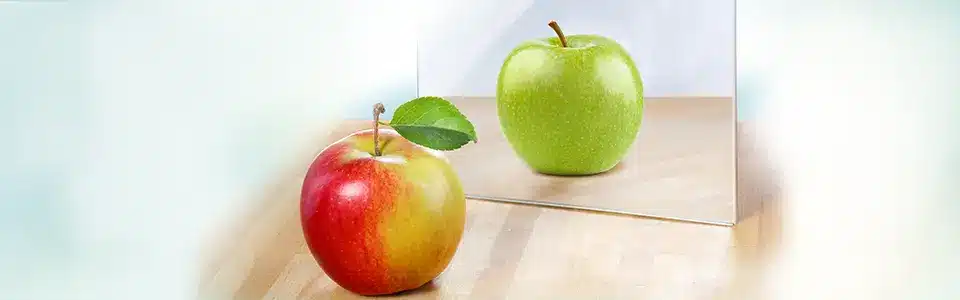 A red apple reflected green in a mirror