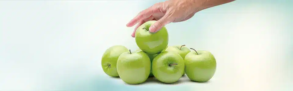 Hand reaching down to select from a group of apples